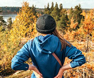 Woman hiked to the top of a mountain overlooking fall leaves and lake